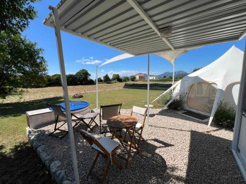 a patio with a table and chairs and a tent at Lisinj Sky Glamping in Bar