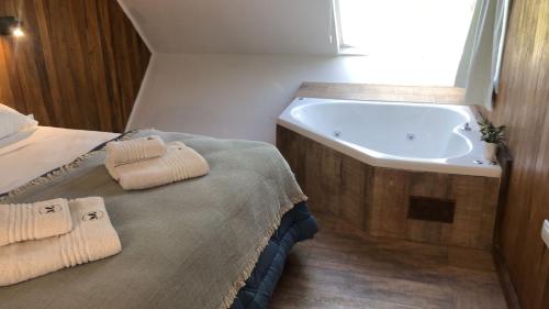 a bathroom with a tub and a bed with towels at Abismo Privado Cabaña de Lujo con Jacuzzi in San Rafael
