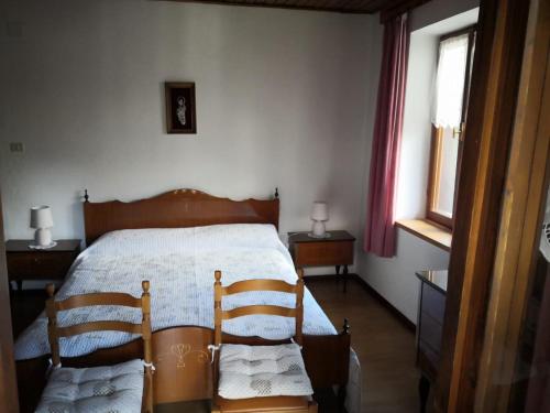 a bedroom with a bed and two wooden chairs at Appartamenti Kratter Valeria in Sappada