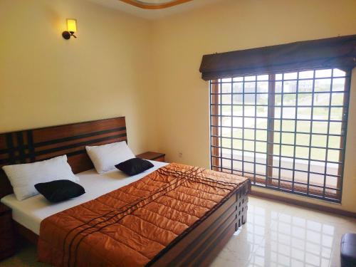 a bedroom with a bed and a large window at The Warmer House Islamabad Airport in Islamabad