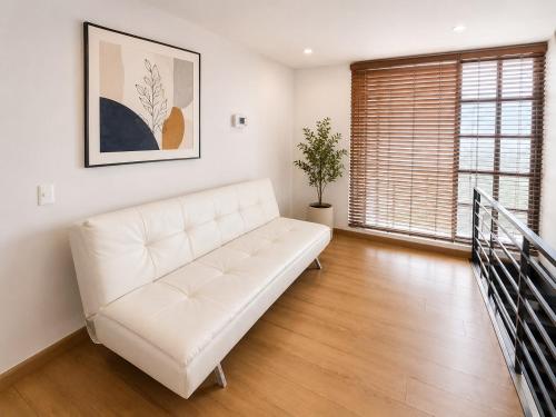 a white couch in a living room with a window at Casa Corferias in Bogotá
