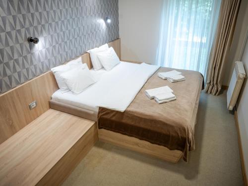 a small bedroom with a bed with white sheets and pillows at Garni Hotel Mlinarev san in Arilje
