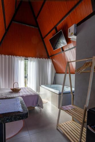 a bedroom with a bed and a tub in a room at Chalé Aliança in Poços de Caldas