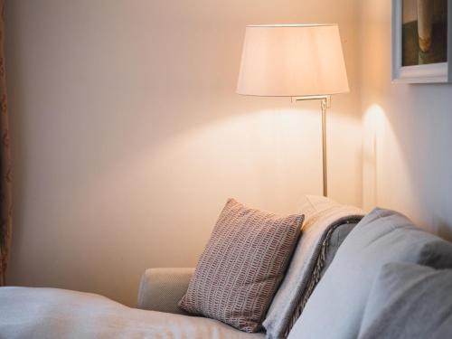 a lamp sitting next to a couch with a pillow at Highfield in Petworth