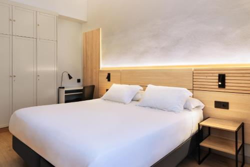 a bedroom with a large white bed and a table at Hospedium Hotel Lleida in Graus