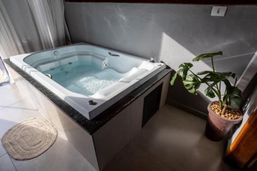 a bath tub in a bathroom with a potted plant at Chalé Aliança in Poços de Caldas