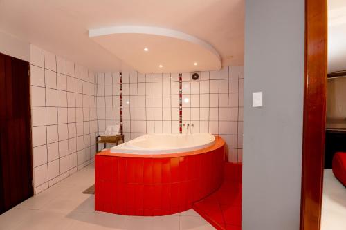a red tub in a bathroom with white tiles at Hostal Los Cactus in Lima