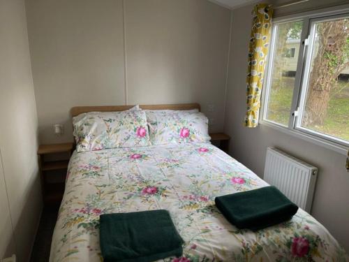 a bed with two green pillows on it in a bedroom at Stylish large static caravan gold rated 3BR Slp 8 Thorness Bay in Porchfield