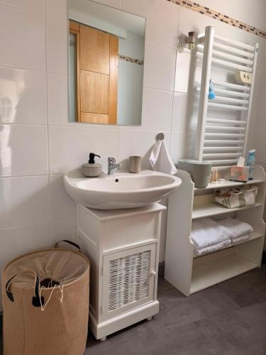 a white bathroom with a sink and a mirror at La maisonnette in Forêt-la-Folie