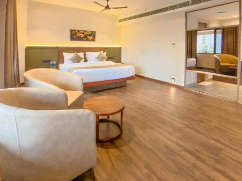 a hotel room with a bed and a couch and chairs at Alora Grand Hotel Calicut in Kozhikode