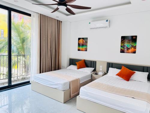 two beds in a room with a ceiling fan at Flamingos Hải Tiến LUXURY view biển tầng cao và Biệt thự 4pn in Thanh Hóa