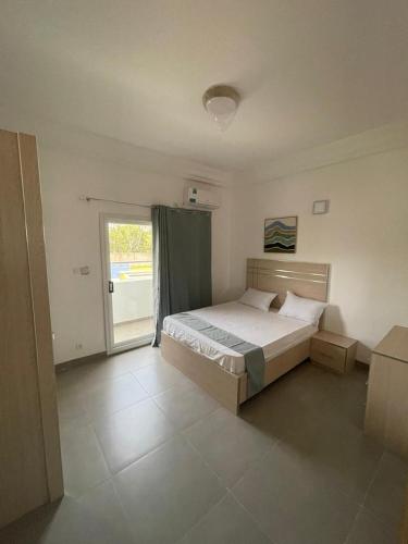 ein Schlafzimmer mit einem Bett und einem großen Fenster in der Unterkunft Cité Soleil in Dakar