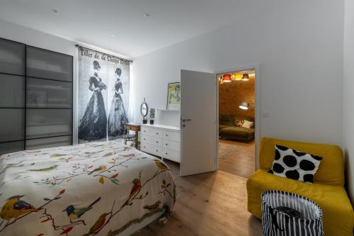 a bedroom with a bed and a yellow chair at Apartment Grof Janko - Luxury in the Center - TERRACE & FREE PARKING in Karlovac