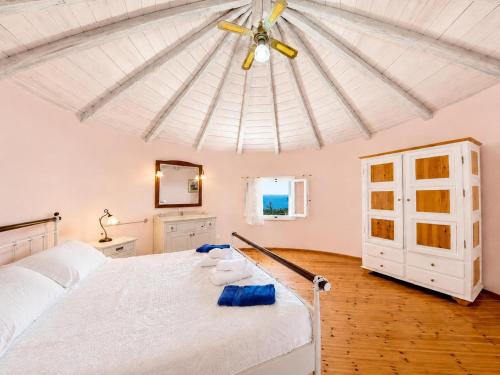 a bedroom with a white bed with a ceiling at Villa Windmill in Vlachopoulátika