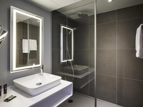 a bathroom with a sink and a shower at Novotel Saclay in Saclay