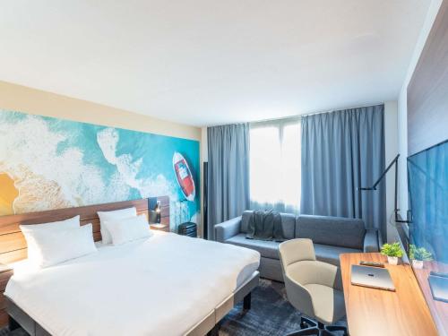 a hotel room with a bed and a couch at Novotel Antibes Sophia Antipolis in Valbonne
