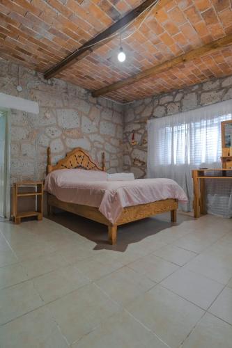 a bedroom with a bed in a stone wall at Hospedaje Las Palmas By GEstores in Huasca de Ocampo