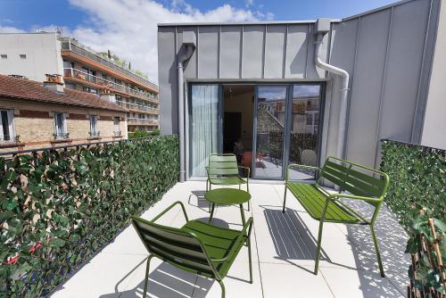 a patio with green chairs on a building at La Maison Solférino in Boulogne-Billancourt
