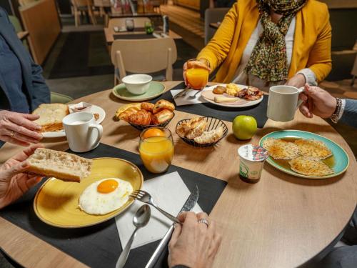a group of people sitting around a table eating breakfast at Novotel Caen Côte de Nacre in Caen