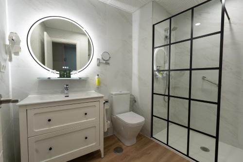 a white bathroom with a toilet and a mirror at Hotel Sercotel Doña Carmela in Seville