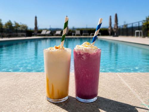 two drinks sitting on a table next to a pool at Ibis Styles Colmar Nord in Colmar