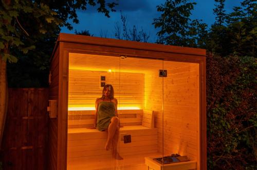 a woman sitting in a sauna at night at Lime weekendhouse 1-2 in Balatonakarattya