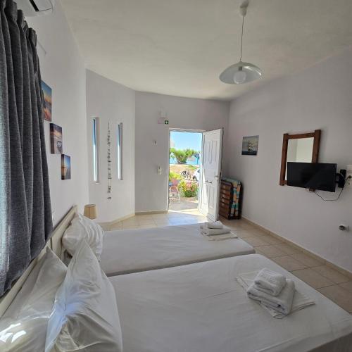 a white room with two beds and a television at Soula appartments in Makry Gialos