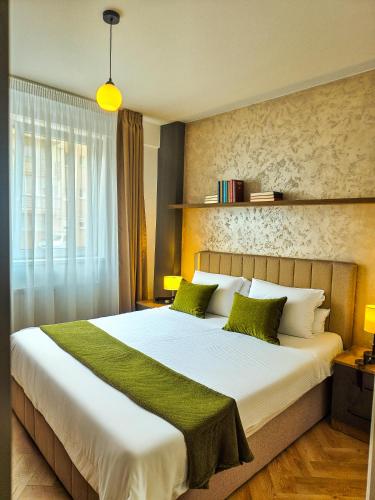 a bedroom with a large white bed with green pillows at Boutique Apartment Suceava Modern Parcare WiFi Rapid in Ipoteşti