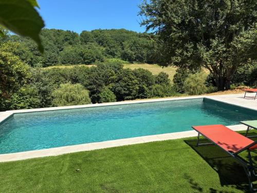 a swimming pool in a yard with a red bench at La Bastide de Sherlock in Troncens