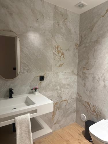 a bathroom with a white sink and a mirror at Apartamento Cimo da Barca in Ponte da Barca