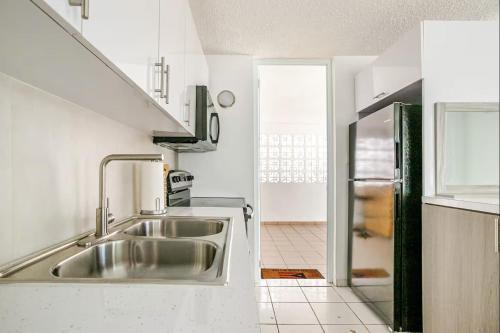 a white kitchen with a sink and a refrigerator at The Mango House in Fajardo