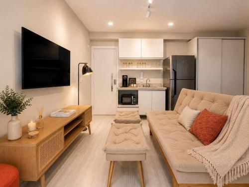 a living room with a couch and a tv and a kitchen at Praça Madá - Anystay in São Paulo