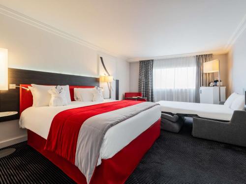 a hotel room with two beds with red and white sheets at Mercure Paris CDG Airport & Convention in Roissy-en-France