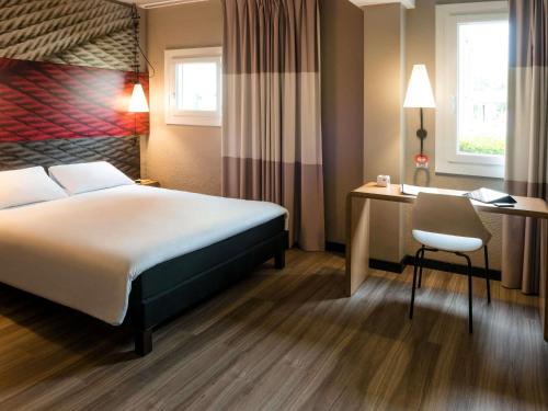 a hotel room with a bed and a desk and a chair at ibis Bourg en Bresse in Bourg-en-Bresse