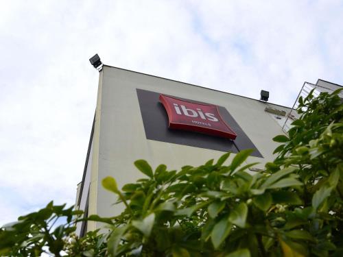 a sign on the side of a building with trees at ibis Chambery in Chambéry