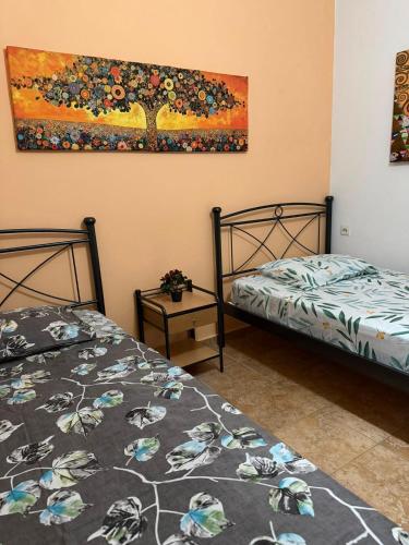 two beds in a room with a painting on the wall at Dimi's Apartment Avdira in Ávdhira