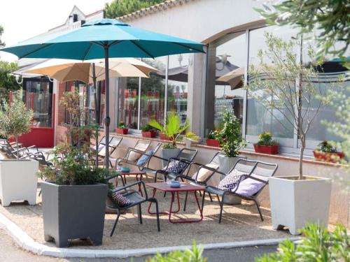 a group of chairs and a table with an umbrella at Hotel ibis Narbonne in Narbonne