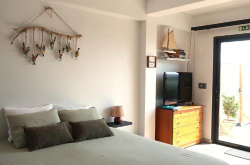 a bedroom with a bed and a tv on a dresser at Seacrets Beach House in Praia do Almoxarife