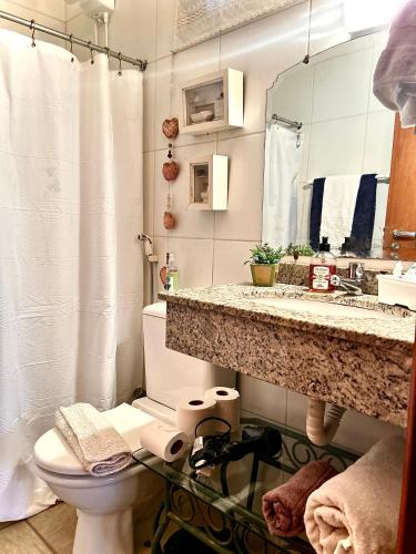 a bathroom with a sink and a toilet and a mirror at Body & Mind Beautiful - Suites Elegantes e Charmosas in Franca
