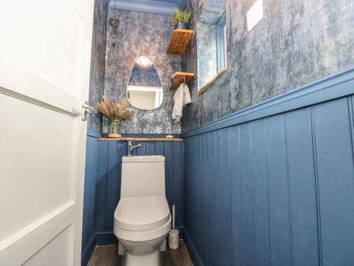 a bathroom with blue walls and a white toilet at Cwtch Ar Y Mor in Burry Port