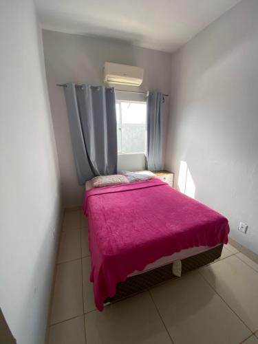 a small bedroom with a pink bed with a window at Flat aconchegante é silencioso in Rio Verde