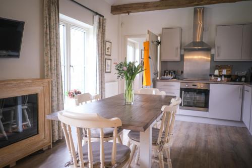 a kitchen with a wooden table with chairs and a vase of flowers at Oaters Wood in Petworth
