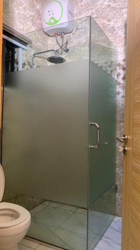 a bathroom with a glass shower with a toilet at Halijomak Apartments in Abuja