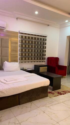 a bedroom with a bed and a red chair at Halijomak Apartments in Abuja