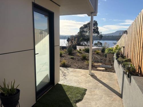 a patio with a view of the water from a house at Derwent Waters Hideway in Austins Ferry