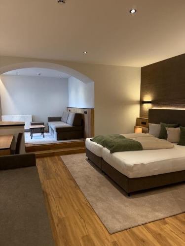 a bedroom with a large bed and a living room at Hotel Gasthof Neuner in Imst
