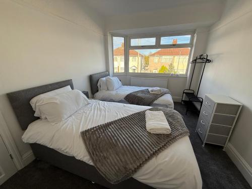 a bedroom with two beds and a window at Short Stay & Long Stay home in Ellesmere Port in Little Sutton