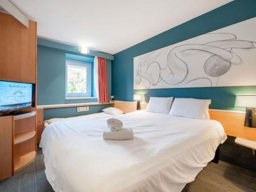 a bedroom with a large white bed and a flat screen tv at ibis Antibes Sophia-Antipolis in Valbonne