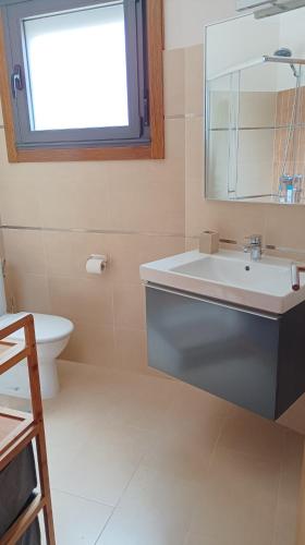 a bathroom with a sink and a toilet and a window at Apartamento La Camelia in Rosal