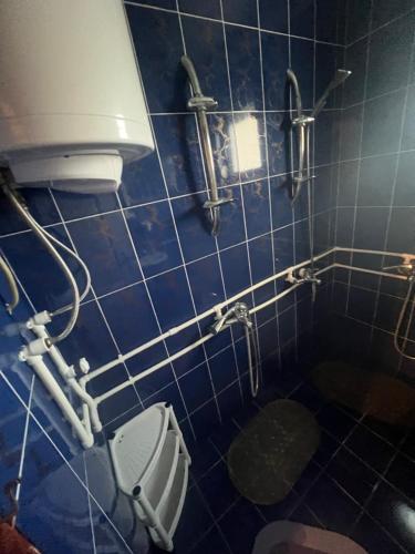 a blue tiled bathroom with a toilet and pipes at Jagoda IN in Otroci